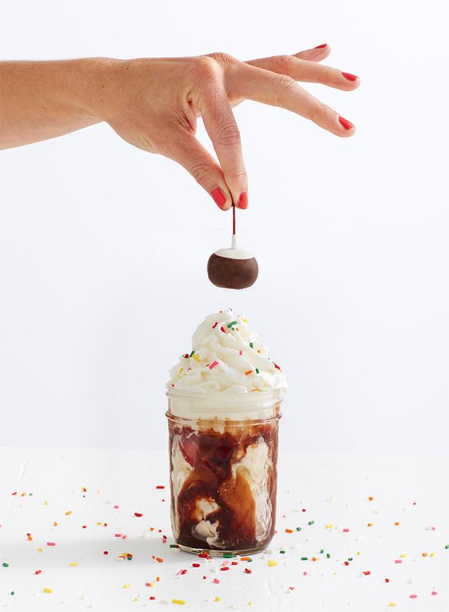 Ice cream cone topped with sprinkles and a cherry